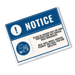A rectangular food safety notice sign with a blue and white design, featuring a warning icon and text listing milk, eggs, wheat, peanuts, tree nuts, fish, and shellfish as potential allergens. The sign is shown at an angle on a plain white background.