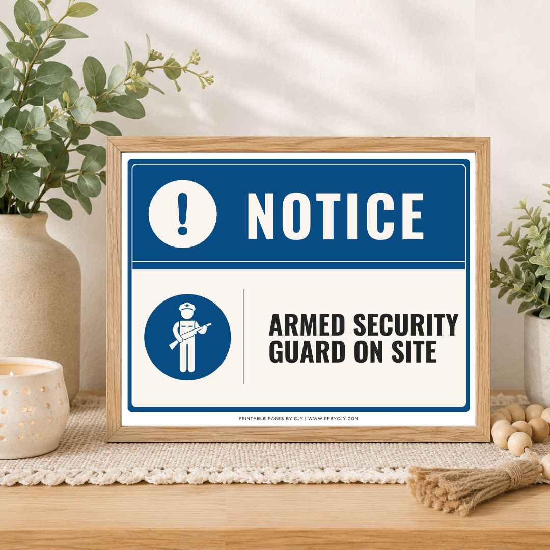 A framed printed notice sign on a tabletop in a styled interior setting. The sign has a blue header with a white exclamation mark and the word NOTICE, and a white lower section with a blue security guard icon and the text ARMED SECURITY GUARD ON SITE.