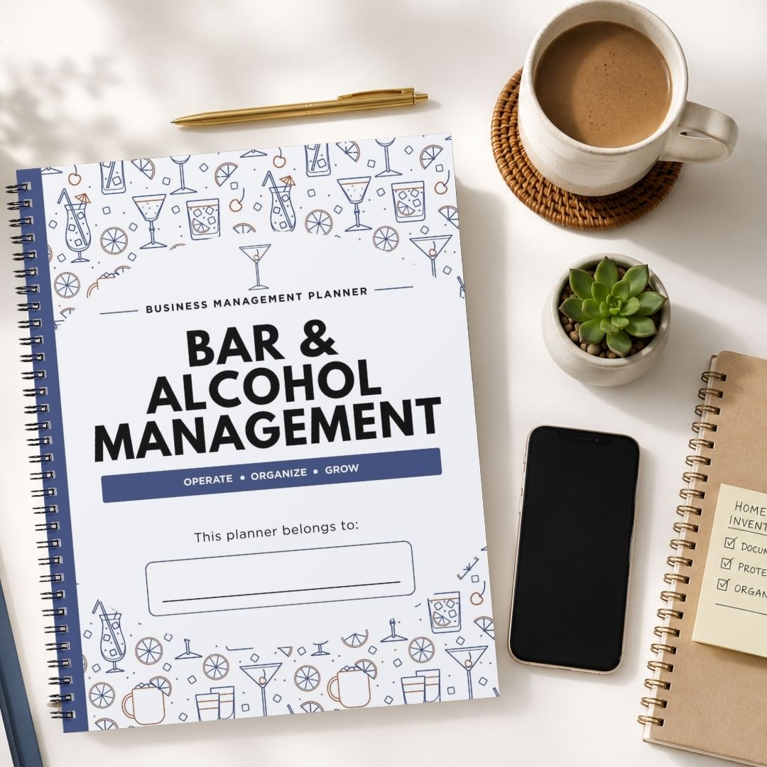A spiral-bound planner titled 'BAR & ALCOHOL MANAGEMENT' lies on a white desk, surrounded by a cup of coffee, a smartphone, a small succulent, and another notebook.