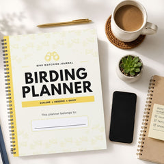 A spiral-bound Bird Watching Journal titled 'BIRDING PLANNER' is shown in a styled flat-lay arrangement on a white surface, alongside a cup of coffee, a pen, a small succulent, a smartphone, and another notebook.