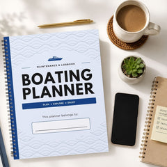 A spiral-bound 'Boating Planner' notebook is displayed in a styled flat-lay arrangement on a white surface, surrounded by a cup of coffee, a pen, a small succulent, a smartphone, and another notebook.