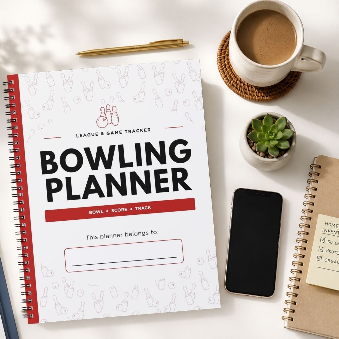 A spiral-bound Bowling Planner tracker notebook is shown in a styled flat-lay arrangement on a white surface, surrounded by a coffee cup, a pen, a small succulent, a smartphone, and another notebook.