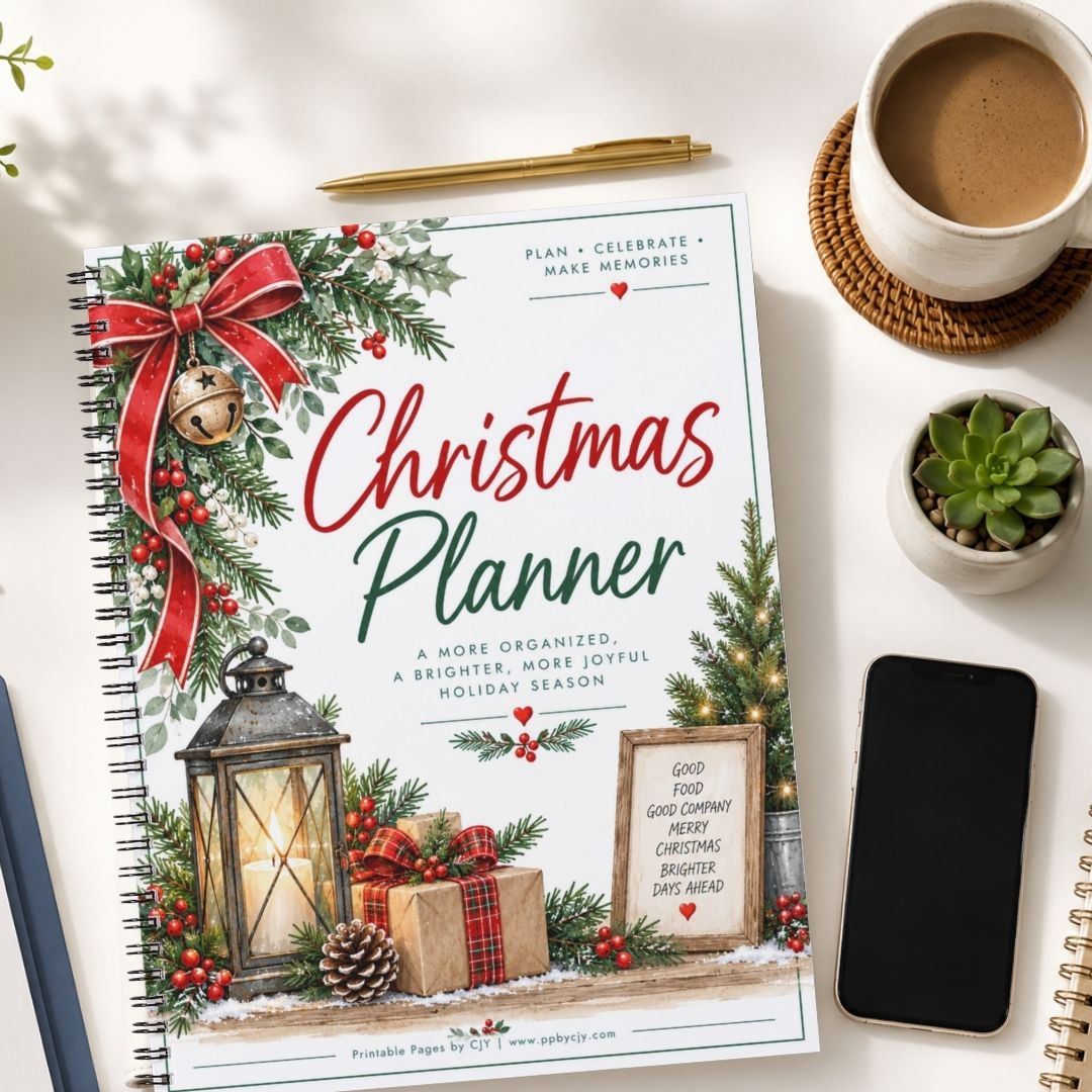A spiral-bound Christmas Planner laid on a white desk, surrounded by a coffee cup, a small succulent, a smartphone, and another notebook. The planner cover features festive illustrations including a red bow, green pine branches, a lantern, wrapped gifts, and the title 'Christmas Planner' in red and green text.