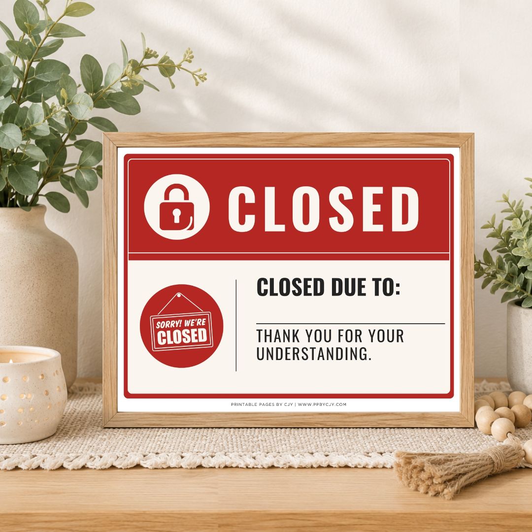 A framed 'Closed' sign with a red and white design sits on a wooden table in a styled home setting with plants and a candle.