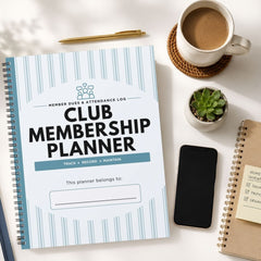 A spiral-bound Club Membership Planner notebook with a white cover and light blue vertical stripes, styled in a flat-lay arrangement on a white desk alongside a cup of coffee, a pen, a small succulent, a smartphone, and another notebook.