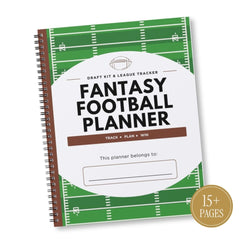 A spiral-bound Fantasy Football Planner shown at an angle on a white background. The cover features a green football field design with white yard lines, a large white oval in the center with the text 'FANTASY FOOTBALL PLANNER' in bold black letters, and a brown band reading 'TRACK + PLAN + WIN'.