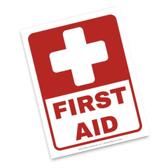 A square red and white First Aid sign with a white cross at the top and the words 'FIRST AID' in large red letters on a white background, shown at a slight angle on a white backdrop.