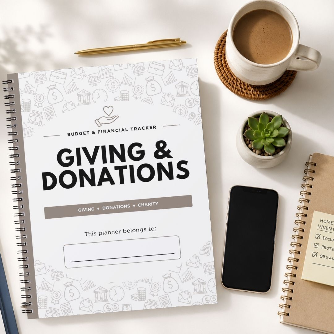 A spiral-bound budget and financial tracker planner titled 'GIVING & DONATIONS' is shown in a styled flat-lay on a white surface, surrounded by a coffee cup, pen, small succulent, smartphone, and another notebook.