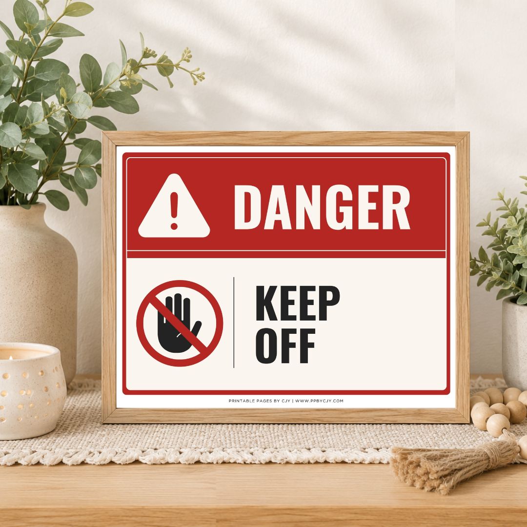 A framed warning sign with a red and white background, featuring the word 'DANGER' and a 'KEEP OFF' hand symbol, styled on a tabletop with plants and home decor.
