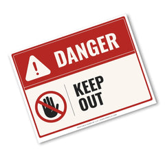 A rectangular warning sign with a red header reading DANGER and a white lower section that says KEEP OUT, plus a hand icon with a red slash. The sign is shown at an angle on a plain white background.