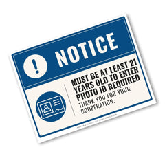 A rectangular blue and white notice sign with bold text reading 'NOTICE' and additional text stating 'MUST BE AT LEAST 21 YEARS OLD TO ENTER PHOTO ID REQUIRED THANK YOU FOR YOUR COOPERATION.' on a plain white background.