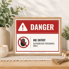 A framed warning sign on a wooden table with decorative plants and candles. The sign has a red and white background with the word 'DANGER' and a 'NO ENTRY' symbol.