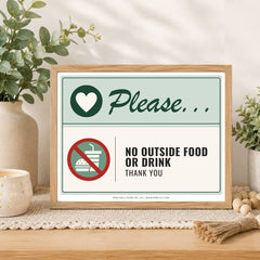 A framed sign on a tabletop in a styled interior setting. The sign reads 'Please.