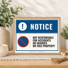 A framed warning sign on a wooden table in a styled home setting. The sign has a blue header with a white exclamation mark and the word 'NOTICE,' and a white lower section with a red-and-blue no symbol and the text 'NOT RESPONSIBLE FOR ACCIDENTS OR INJURIES ON THIS PROPERTY.
