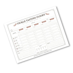 A printable 'Pickle Tasting Flight' chart sheet shown at an angle on a white background. The sheet features a grid with columns for days of the week and rows for flavors, with small illustrations of pickled foods like onions, carrots, and peppers.