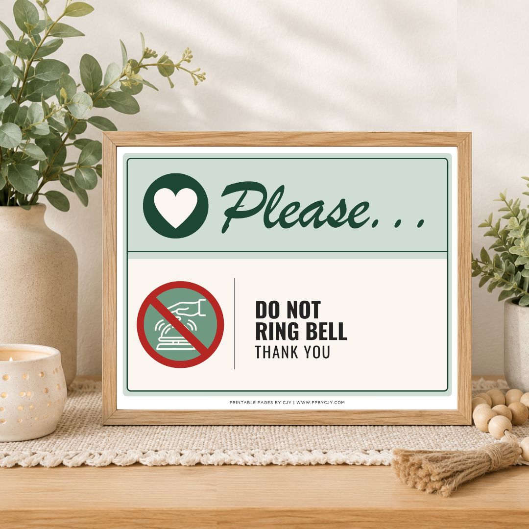 A framed printed sign on a wooden table in a styled interior setting. The sign reads 'Please.