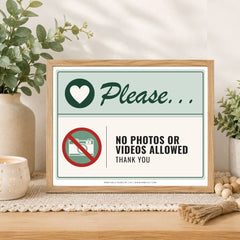 A framed printed sign on a tabletop in a styled interior setting. The sign reads 'Please.