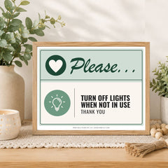 A framed printable sign on a wooden table in a styled room setting. The sign has a light wood frame and a two-tone design with sage green and cream sections.