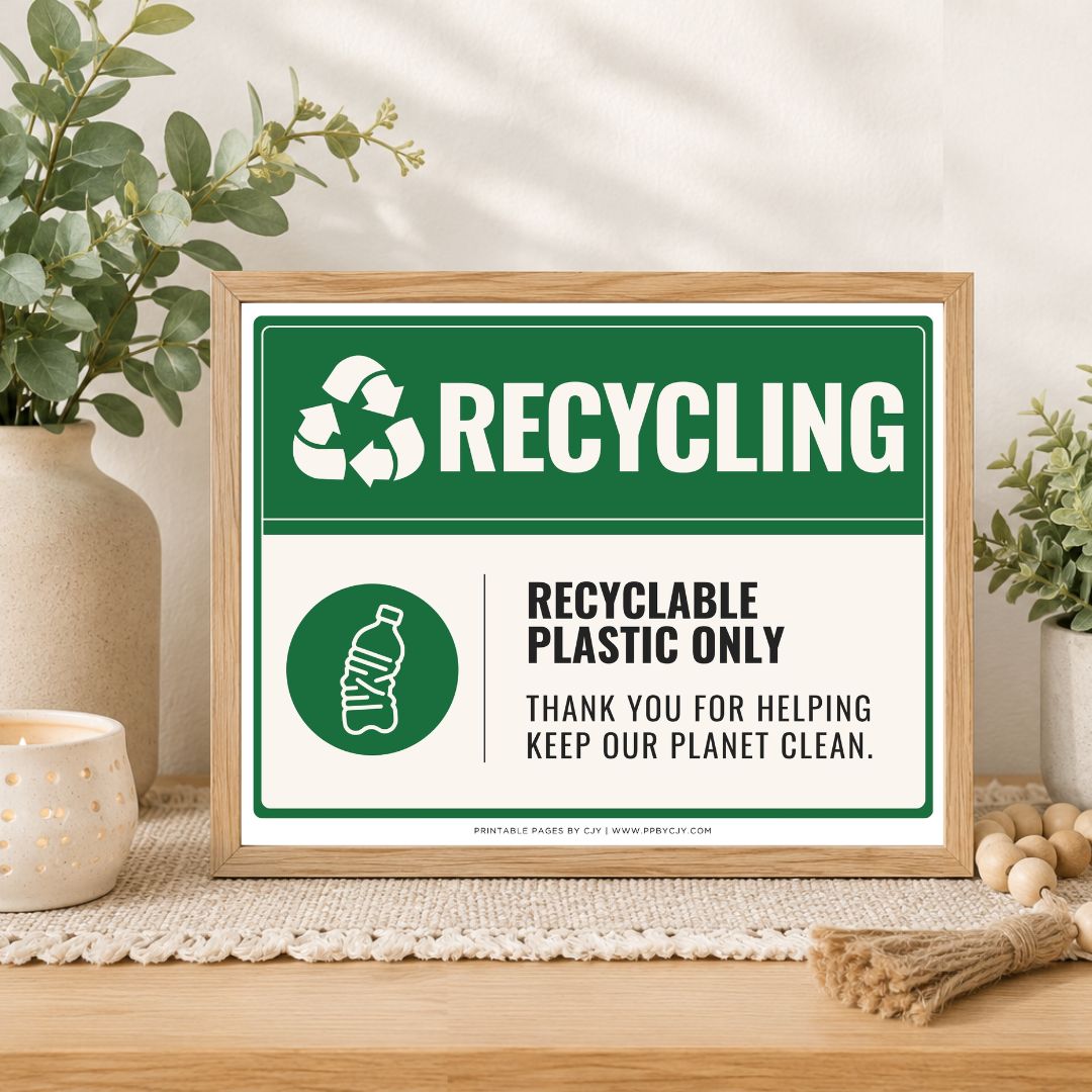 A framed recycling sign on a wooden table in a styled home setting. The sign has a green and white design with the text 'RECYCLING' and 'RECYCLABLE PLASTIC ONLY.