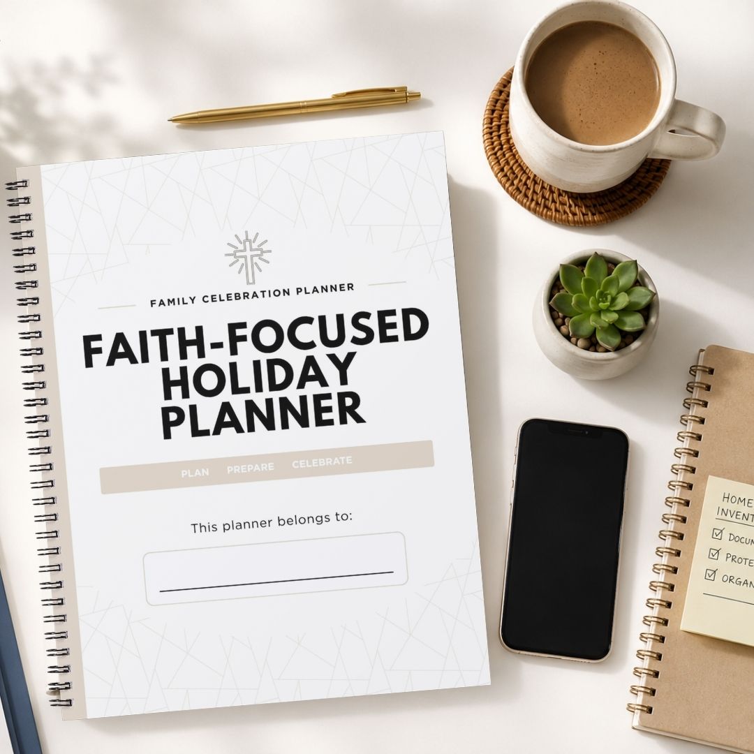 A spiral-bound 'Faith-Focused Holiday Planner' notebook is shown in a styled flat-lay arrangement on a white surface, surrounded by a cup of coffee, a small succulent, a smartphone, and other notebooks.