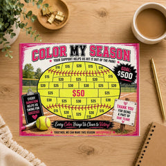 A 'Color My Season' baseball-themed fundraising game board displayed on a wooden desk, surrounded by a coffee cup, plant leaves, a bowl of gold coins, and a notebook.