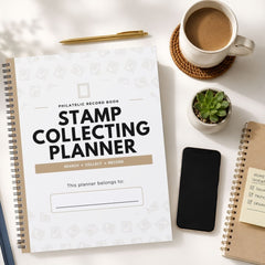A spiral-bound 'Philatelic Record Book' titled 'Stamp Collecting Planner' is displayed in a styled flat-lay arrangement on a white surface, surrounded by a cup of coffee, a pen, a small succulent, a smartphone, and another notebook.