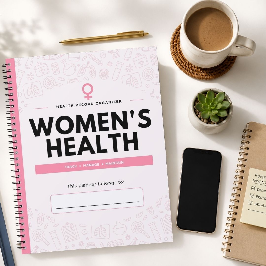A spiral-bound Women's Health planner is shown in a styled flat-lay arrangement on a white surface, alongside a cup of coffee, a small succulent, a smartphone, and another notebook.