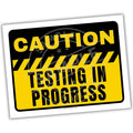 Caution sign with 'Testing in Progress' text on a white background