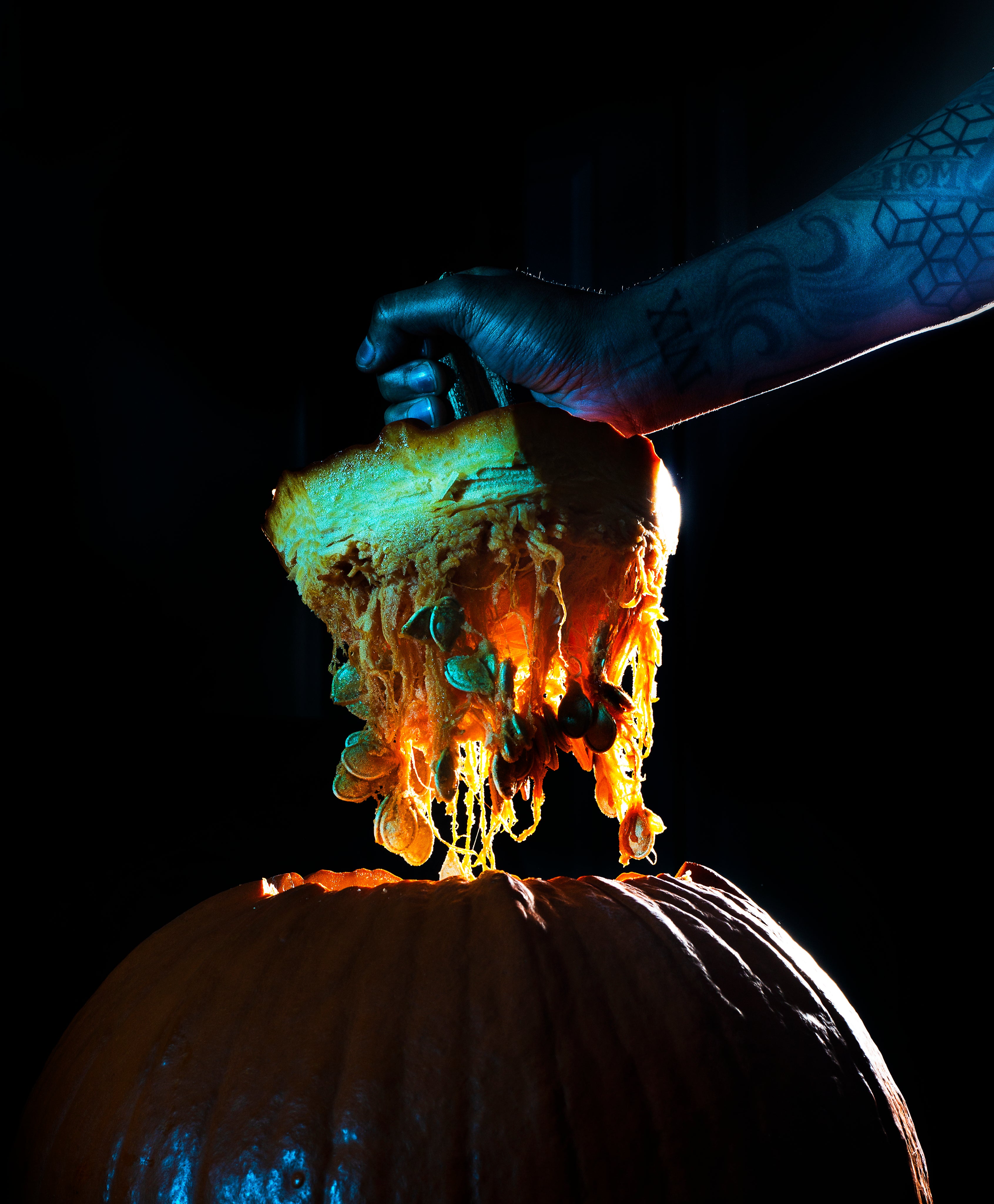 a person lifting the top off a freshly carved pumpkin.
